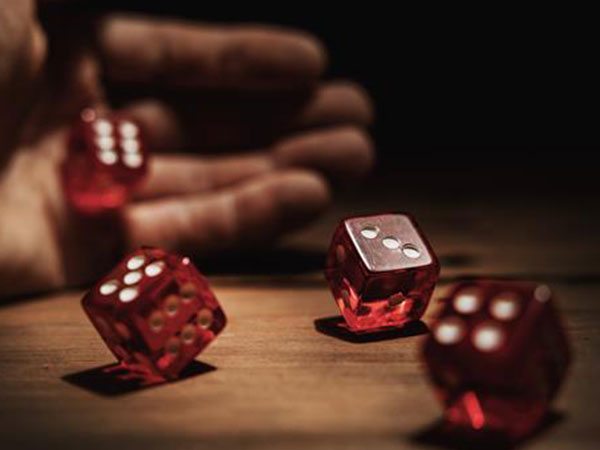 closeup shallow focus photo of a hand rolling four red dice