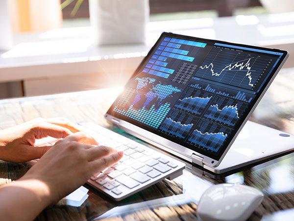 photo of a person typing on a laptop displaying several different graphs