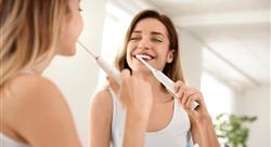 woman brushes teeth with eletric toothbrush