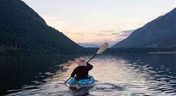 a lone person kayaking on a mountain lake